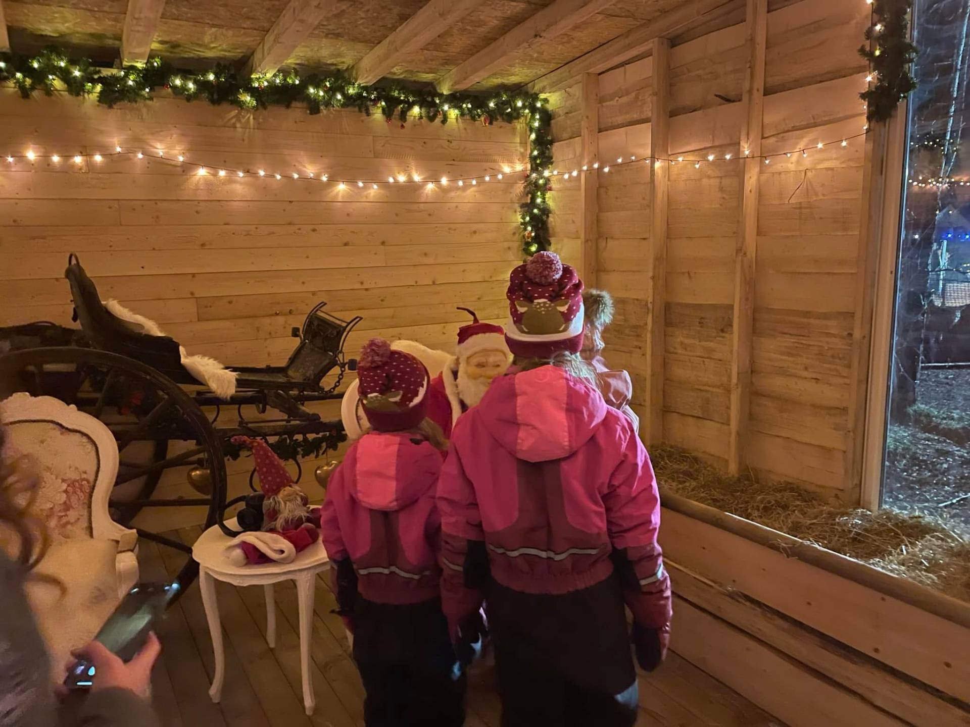 Barn møter julenissen i pyntet låve